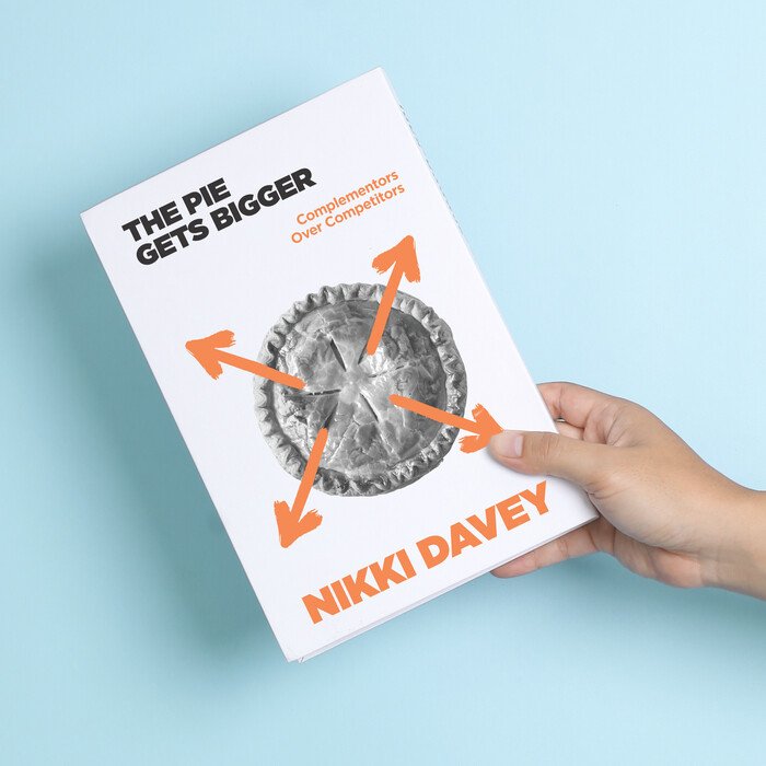A hand holding The Pie Gets Bigger by Nikki Davey