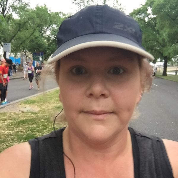 Nikki mid-run in a cap during a running event