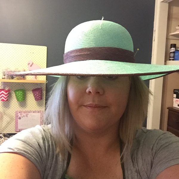Nikki wearing a wide-brimmed green straw hat with the pins still in
