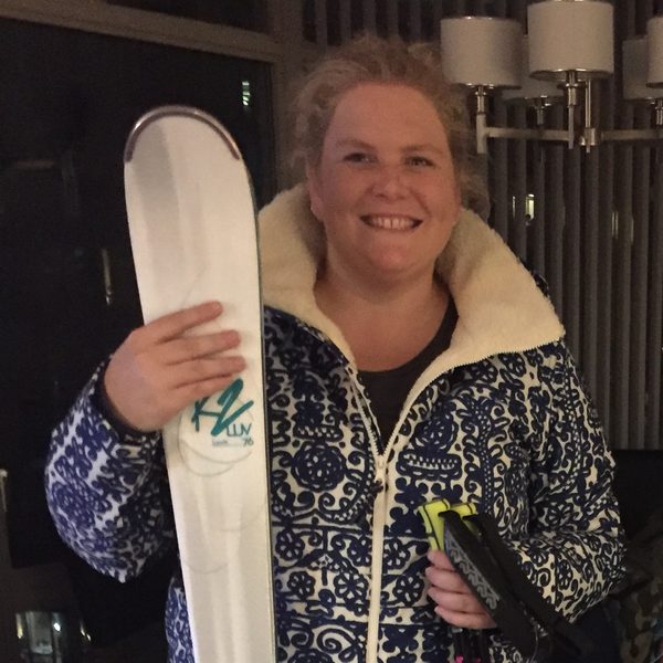 Nikki in ski gear holding a pair of skis