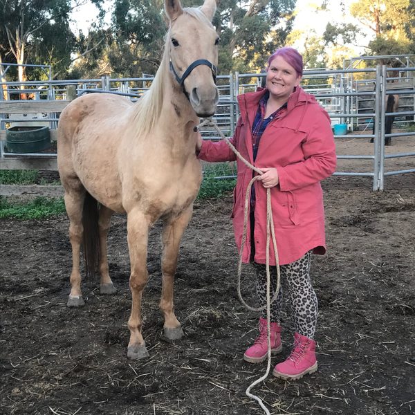 Nikki holding the lead rope of a palomino horse