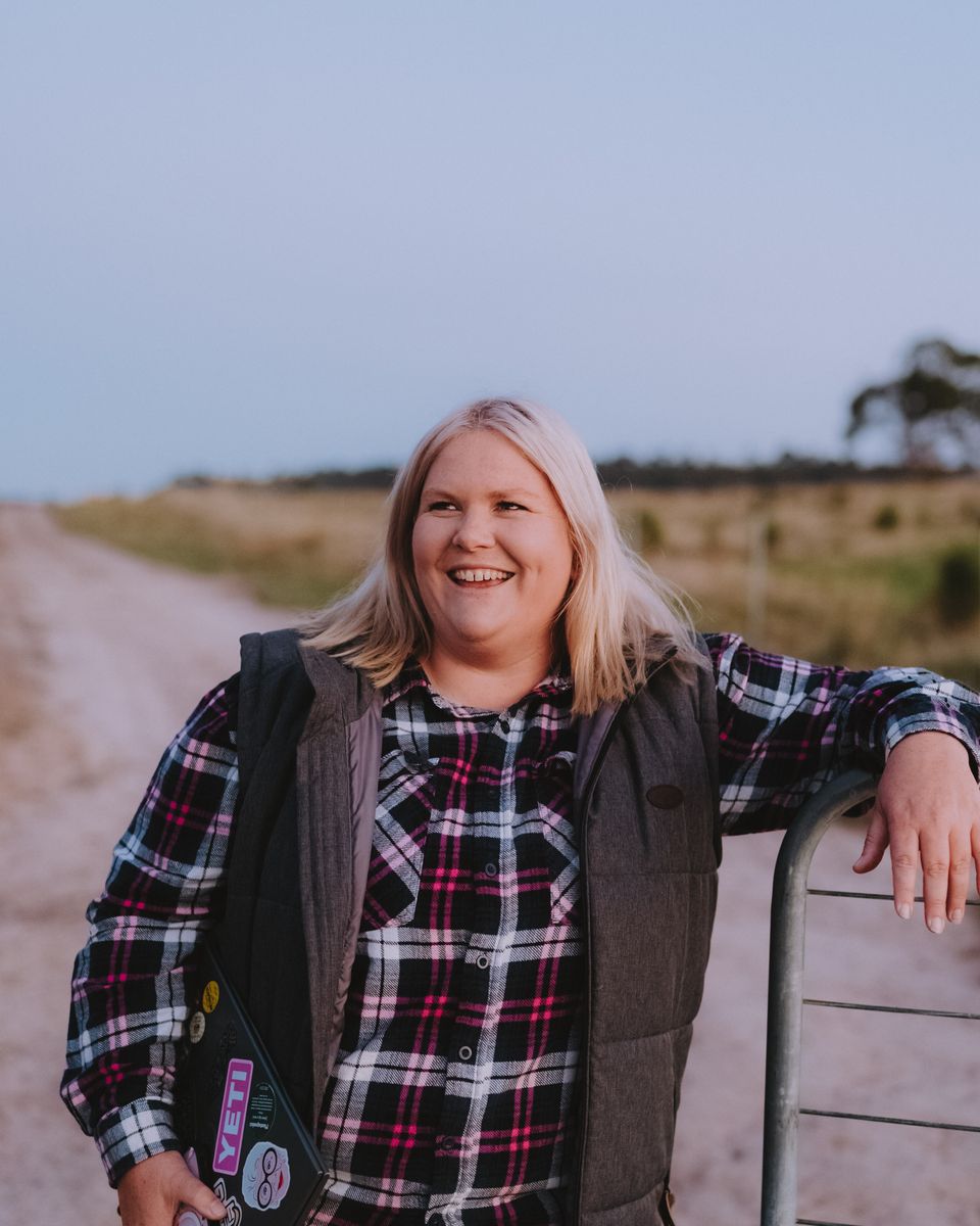 Nikki laughing, leaning on a farm gate