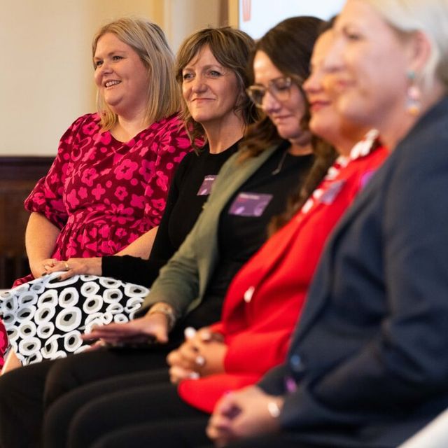 Nikki smiling, seated on a panel